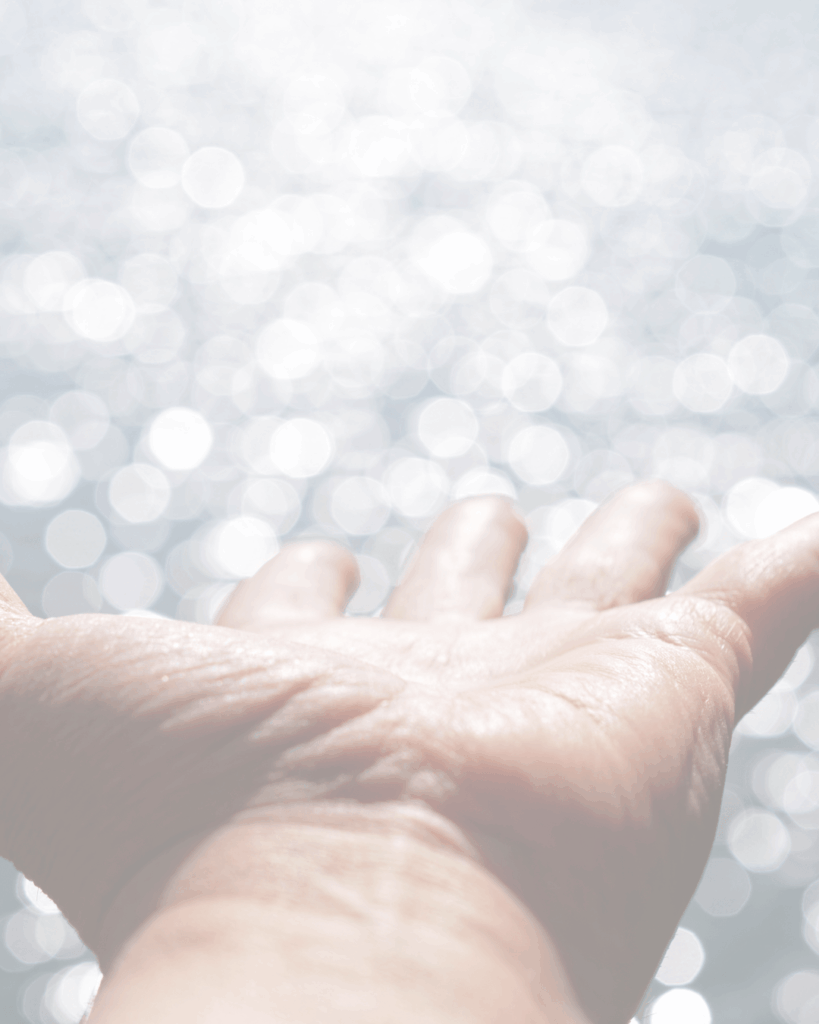 Main ouverte tendue vers une lumière diffuse et scintillante sur fond clair.